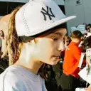 Çok dilli Tom Kaulitz sohbet IA görevlerine odaklanıyor, arka planda sinir ağı çekirdeği görünüyor.