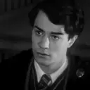 Multilingual Tom Riddle focusing on chat IA tasks, neural network core visible in background.
